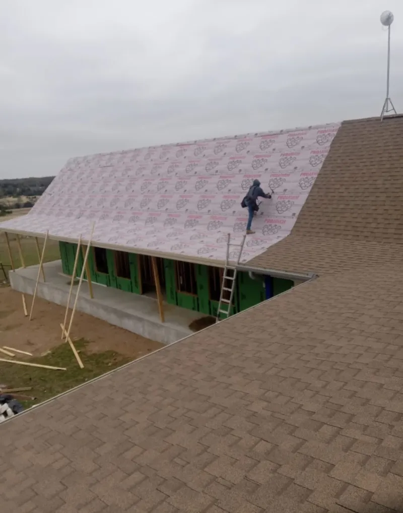Worker preparing underlayment for a metal roof installation in Pacifica